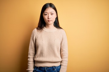 Young beautiful asian woman wearing casual sweater over yellow isolated background Relaxed with...