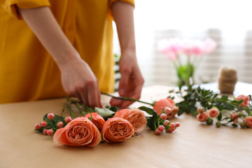Unrecognizable young woman wearing mustard yellow shirt making a beautiful bouquet of flowers. Female florist at work concept. Close up, copy space, background.