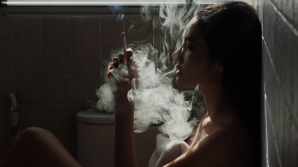 Asian woman inhaling and cigarette vaping. Female secretly smoking in bathroom at home. Concept of quit smoking and anti cigarette.