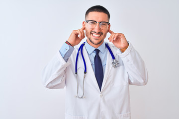 Young doctor man wearing stethoscope over isolated background covering ears with fingers with annoyed expression for the noise of loud music. Deaf concept.