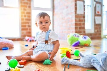 Adorable toddler playing around lots of toys at kindergarten