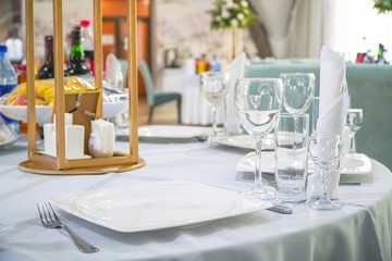 The table in the restaurant is served for lunch. On a table with a white tablecloth, empty wine glasses, a plate, napkins. Selective focus