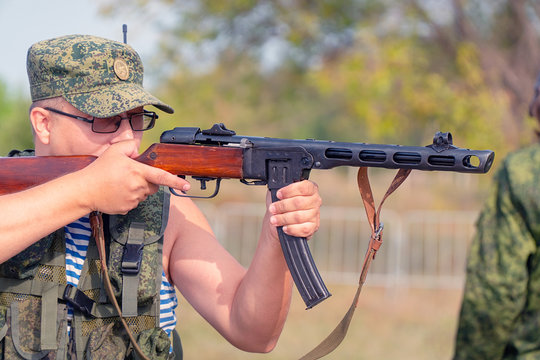 A soldier in camouflage uniform shoots from an old Russian machine gun from the second world war