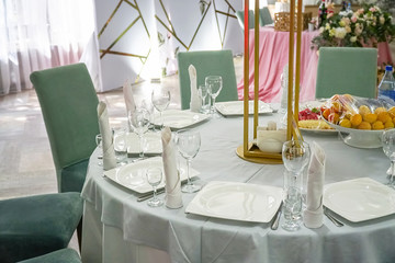 The table in the restaurant is served for dinner. On a table with a white tablecloth, empty wine glasses, a plates, napkins. Selective focus