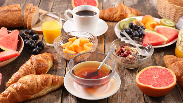 full breakfast with coffee cup, tea cup, croissant, bread and fruit