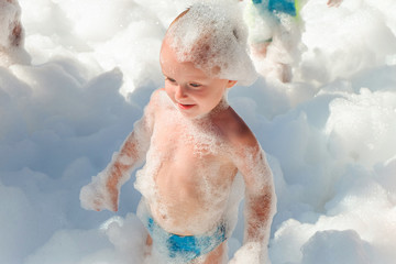 Little boy in airy foam on a dance party floor. Foamy children disco party.