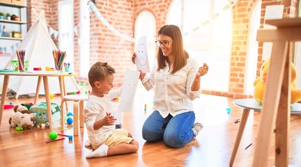 Obraz premium Beautiful psiychologist and toddler doing therapy around lots of toys at kindergarten