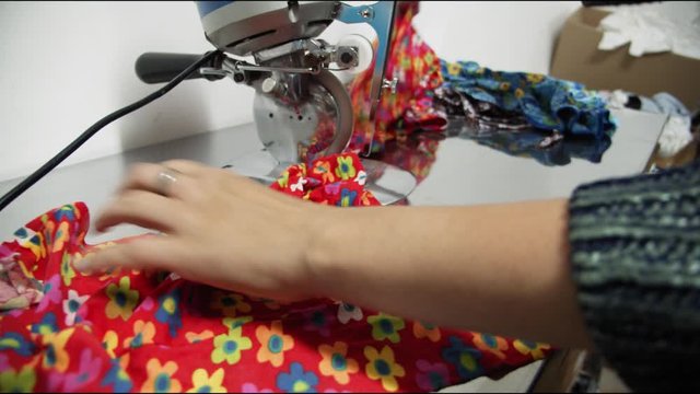 woman cuts bright fabric sheet with special knife in shop