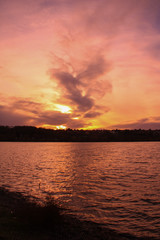 Fototapeta premium Romantic and bucolic sunset behind the horizon. Reflections of sun rays in the water at night.