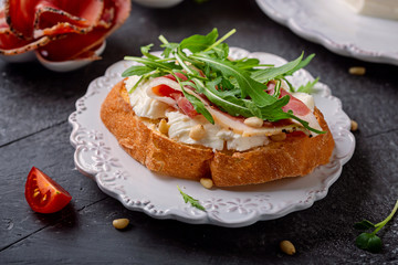 Sandwich with Italian  cheese Stracchino , arugula, prosciutto and pine nuts. Close up