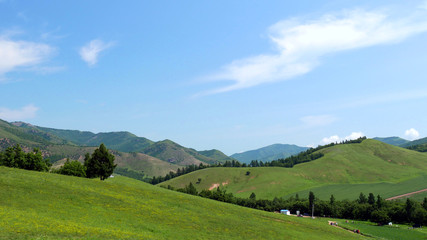 Green mountains in the summer sunlight against the blue sky