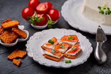 Canape  from  crackers with soft  cheese stracchino , tomato slice and green leaf.  