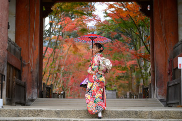 woman holding retro umbrella in old fashion style traditional kimono, walks alone in the middle of...