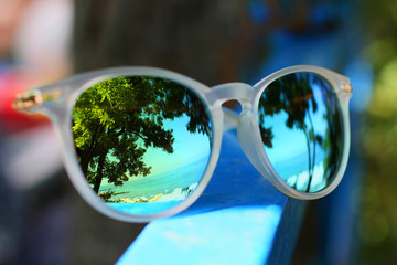 Reflective sunglasses with reflection of the sea and trees.Summer concept.