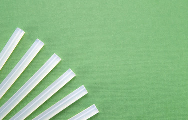 The transparent rods for the glue gun neatly fan out on a green background (table) in the corner. Sticks for thermal gun.