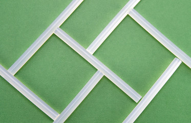 Unusual abstraction from transparent sticks on a green background. The rods are folded into uneven squares.