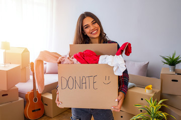 Woman hand holding donation box with clothes, toys and books. Young woman with donation box at...