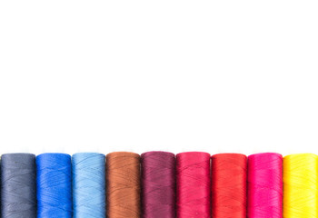 Spools with threads of different colors for embroidery and needlework. Lie in a row on a white isolated background. Multi-colored threads for hobbies and sewing. Abstraction