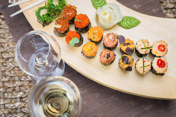 Set of several different rolls on a wooden stand on a table in a Japanese restaurant. Japanese traditional sushi and rolls.