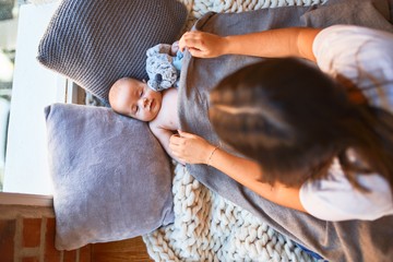 Young beautifull woman and her baby on the floor over blanket at home. Newborn and mother relaxing and resting comfortable with doll