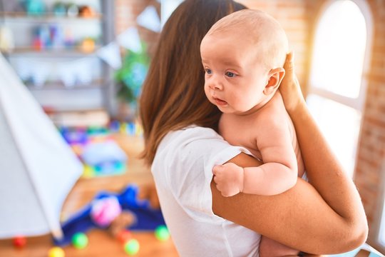 Young beautifull woman and her baby standing at home. Mother holding and hugging newborn