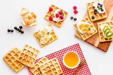 Belgian waffles with creamy cheese and berries on white background top-down