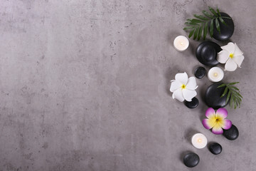Obraz na płótnie Canvas Spa procedure attributes, face and body cream & plumeria flowers, grunged stone textured table background. Retinol moisturizing anti aging antioxidant skincare product for women. Copy space, close up.