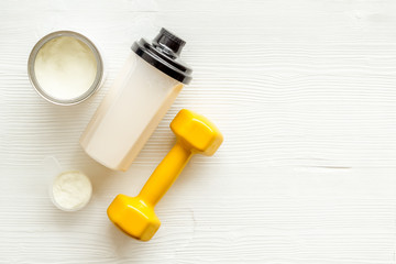 Sport diet. Protein shake near dumbbells on white background top-down flat lay copy space