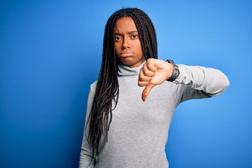Young african american woman standing wearing casual turtleneck over blue isolated background...