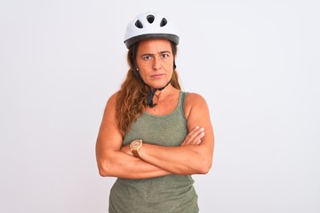 Middle age mature cyclist woman wearing safety helmet over isolated background skeptic and nervous, disapproving expression on face with crossed arms. Negative person.