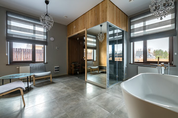 Luxury bathroom with white bathroom, glass shower, sauna. The combination of marble and wood in interior design