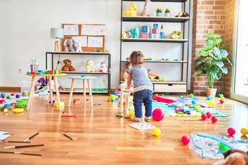 Beautiful toddler standing around lots of toys at kindergarten