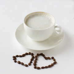 White coffee cup with plate and cofee beans in heart shape isolated on white.