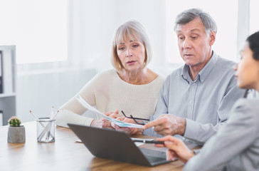Focused mature couple talking to financial advisor at home
