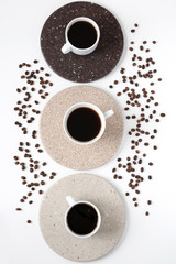 Round coasters made of artificial stone tabletop on a white background. Food stand. Three coffee mugs top view. 