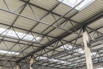 Aluminum roof with windows on a metal frame. Two reinforced concrete beams hold the structure. Construction of the hangar.