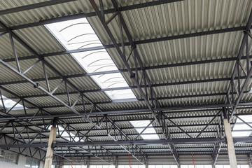 Aluminum roof with windows on a metal frame. Two reinforced concrete beams hold the structure. Construction of the hangar.