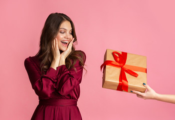 Excited young woman in evening dress getting surprise gift box