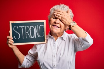 Senior beautiful woman holding blackboard with strong message over isolated red background stressed with hand on head, shocked with shame and surprise face, angry and frustrated. Fear and upset