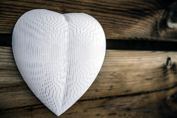 Plastic lonely heart hanging on a wooden wall