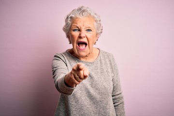 Senior beautiful woman wearing casual t-shirt standing over isolated pink background pointing displeased and frustrated to the camera, angry and furious with you - Powered by Adobe