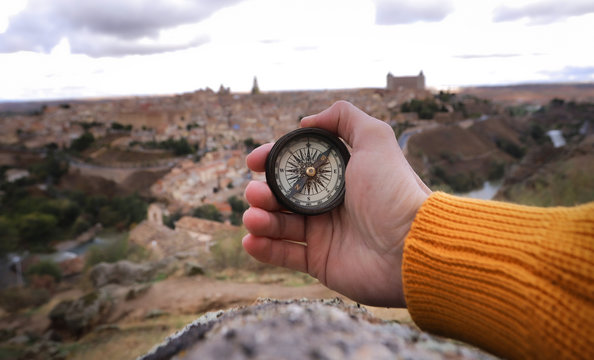 una mano con una brujula y en el fondo toledo