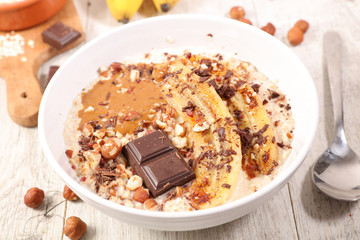 bowl of oatmeal, cereal porrdige with banana, nut and chocolate