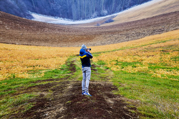 Fototapeta premium Nature photographer. Man with a camera in nature on a cold day.Travel and memories. Alaska
