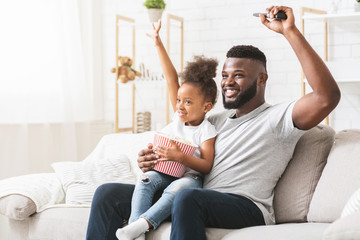 African father and daughter football fans watching game together