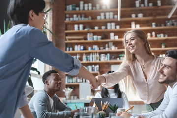 Young guy and girl shaking hands during business training