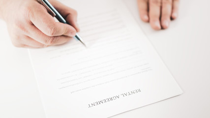 Closeup of a businessman  signing a rental agreement with a pen.