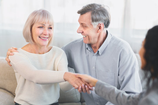 Happy elderly couple giving female doctor handshake