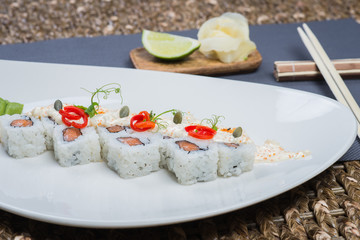 Traditional rolls with fish and rice on a white plate with sauce and wasabi. Japanese food.