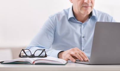 Unrecognizable senior man using laptop at home